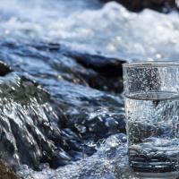 Glass of water with flowing stream in background. Sourced from istock. copyight restrictions apply