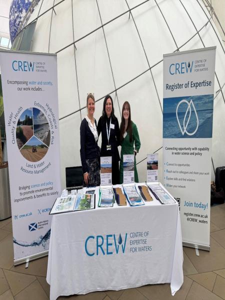 CREW stand with three staff at conference